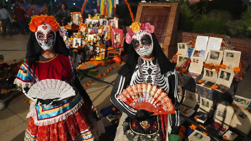Gente junto a puestos de la calle Olvera en una procesión nocturna durante el Día de Muertos,...